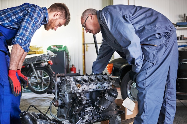 Mechanics inspecting a car engine during a repair at an automotive workshopz